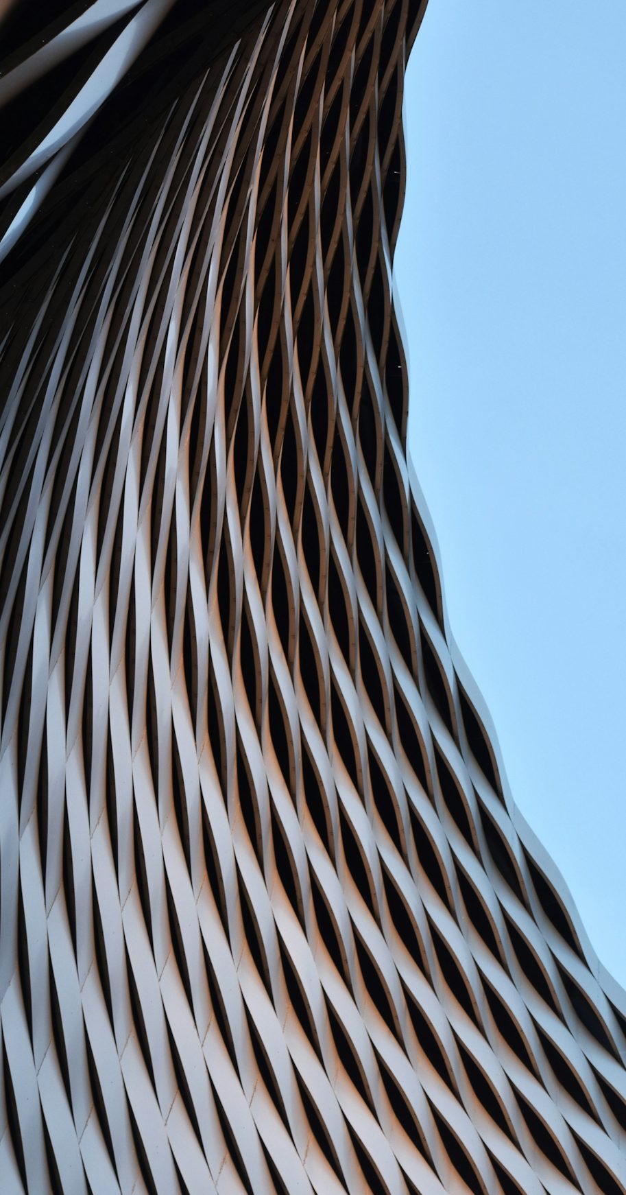 Curved metallic pattern against a blue sky, creating a dynamic visual effect.